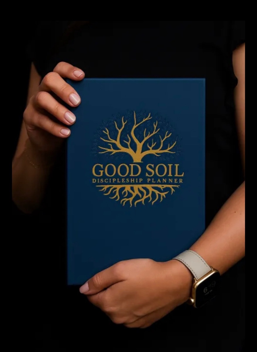The blue Good Soil Discipleship Planner with its gold tree cover, held in two hands